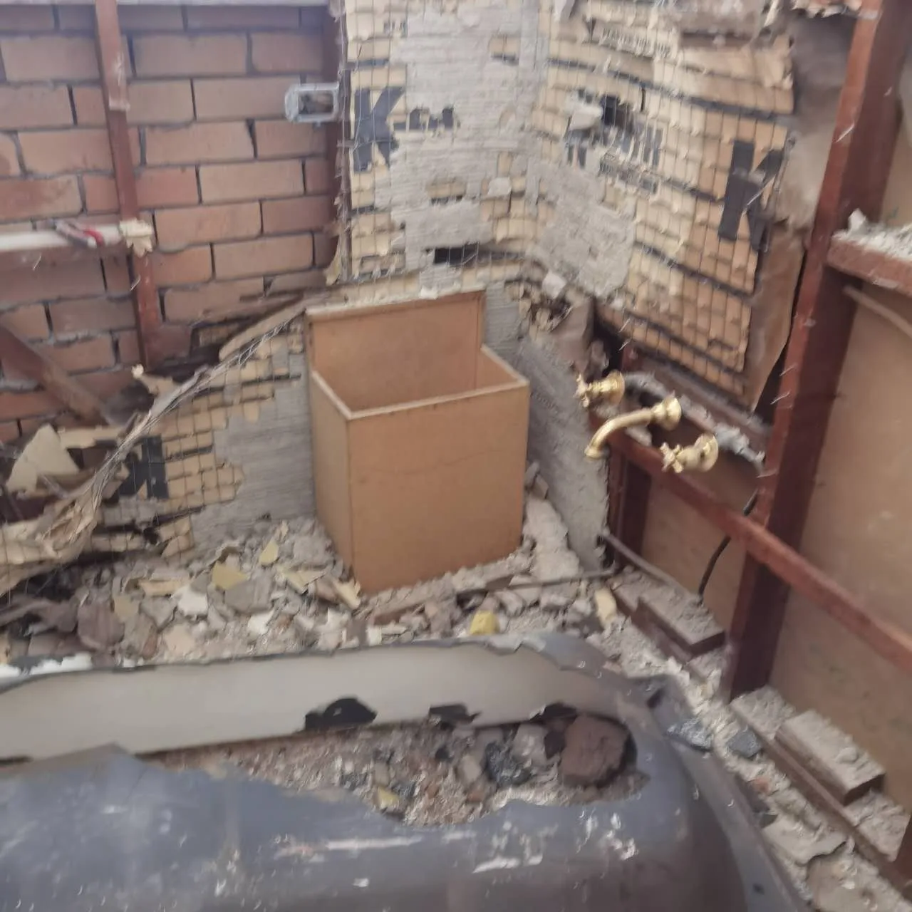 Owner-supplied bathroom demolition-stage photo showing opened wall and fixture area