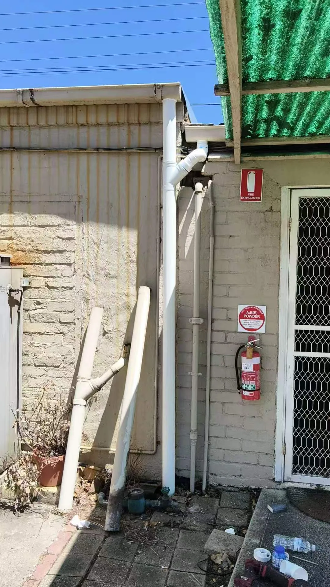 Owner-supplied wide view of an exterior vertical pipe route and surrounding access